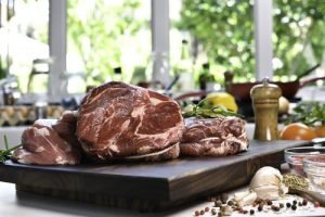 Fresh raw pieces of beef meat with ingredient on a cutting board in the kitchen